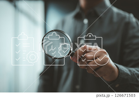 Businessman inspecting checklists with magnifying glass through digital quality control icons. 126671503