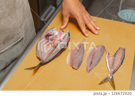 男性が魚のアジをさばいている素材写真　背開きと三枚おろしを並べている 126672020
