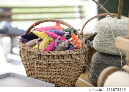 Handweaving Yarn Spools in Wicker Basket 126673396