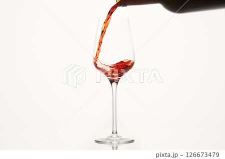Red wine stream flows, swirls in glassware bowl. 126673479