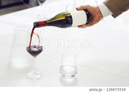 Expert Sommelier Pouring Red Wine to the Glass, Close up Indoor Photo. Preparation to blind wine tasting for beginners sommelier. 126673534