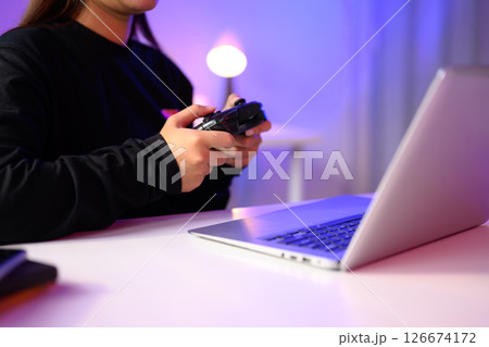 Close up of gamer holding a console controller while playing on a laptop Close up of gamer holding a console controller while playing on a laptop 126674172