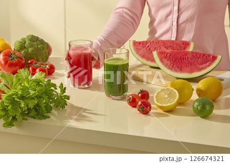 A kitchen island filled with fresh vegetables and fruits like while someone prepares a healthy smoothie. Colorful watermelon, lemon, tomato and celery on modern kitchen background 126674321