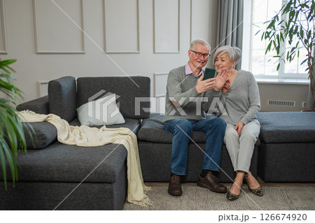 Video call. Happy senior couple woman man with smartphone having video call. Mature old grandmother grandfather talking speaking online. Older generation modern tech usage. Virtual meeting online chat Video call. Happy senior couple woman man with smartphone having video call. Mature old grandmother grandfather talking speaking online. Older generation modern tech usage. Virtual meeting online chat 126674920