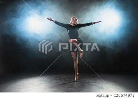 Contemporary woman dancer posing on black background with smoke. Adult female artist performer dancing with expression. Modern ballerina dancing in darkness. Passion dance in dark. Flexibility balance Contemporary woman dancer posing on black background with smoke. Adult female artist performer dancing with expression. Modern ballerina dancing in darkness. Passion dance in dark. Flexibility balance 126674978