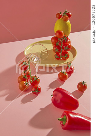 The minimalist aerial shot of fresh produce like ripe tomatoes and juicy red bell peppers is garnished on a pretty pink surface, creating a warm feeling to the dish 126675328