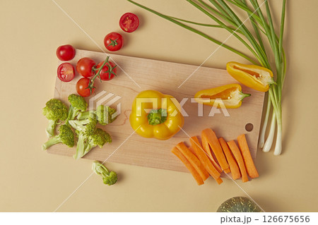 Artistic flat-lay of green vegetables and fruit arranged symmetrically on a rustic beige background. Includes broccoli, zucchini, cucumber, and mint, ideal for organic food themes 126675656