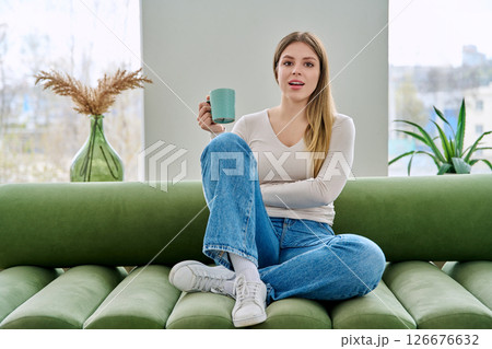 Portrait of relaxed beautiful young woman sitting at home on sofa with cup Portrait of relaxed beautiful young woman sitting at home on sofa with cup 126676632