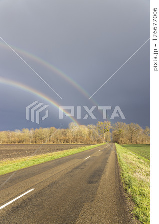 Double rainbow appearing over asphalt road crossing countryside 126677006
