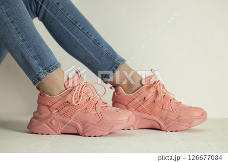 detail of sitting woman wearing pink trainers and jeans detail of sitting woman wearing pink trainers and jeans 126677084
