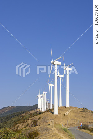 Wind turbines generating clean energy on a hilltop under a clear blue sky 126677230