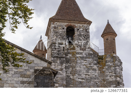 Church bell tower with conical roofs in Auvillar, France, showing stone walls and cloudy sky Church bell tower with conical roofs in Auvillar, France, showing stone walls and cloudy sky 126677381