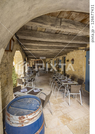 Outdoor restaurant under medieval arches showing wooden ceiling and wine barrel in La Romieu, France 126677431
