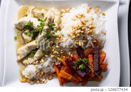 Chicken breast with rice, pine nuts, carrots and beetroot, garnished with chives Chicken breast with rice, pine nuts, carrots and beetroot, garnished with chives 126677434