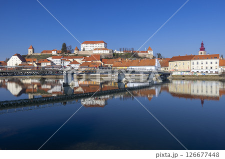 Ptuj Castle reflecting on the Drava River with a pedestrian bridge in the foreground, Slovenia 126677448