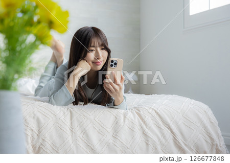 ベッドでスマホを見る女性 ベッドでスマホを見る女性 126677848
