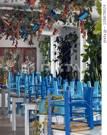 A traditional Cypriot outdoor taverna with blue chairs and tables beneath autumn foliage, evoking local charm. 126678024