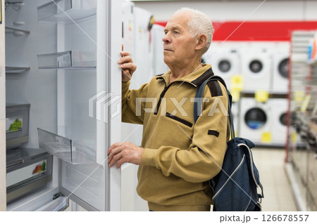 Senor man pensioner buying fridge in showroom of electrical appliance store 126678557
