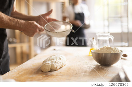 Baker's hands sifting flour on dough 126678563