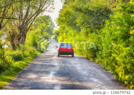 Road into the distance with red car. 126679782