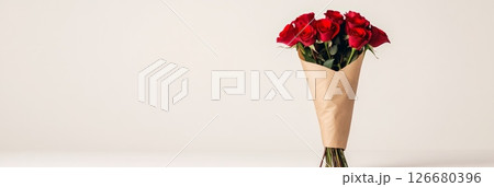 Beautiful bouquet of red roses wrapped in brown craft paper, standing upright against a minimalist white background, creating an elegant composition for romantic occasions Beautiful bouquet of red roses wrapped in brown craft paper, standing upright against a minimalist white background, creating an elegant composition for romantic occasions 126680396