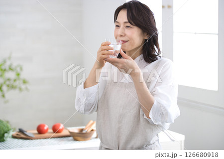 キッチンで水を飲む笑顔のミドル女性 126680918