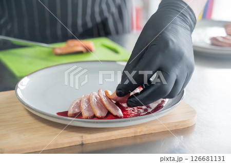 The chef places the duck on cranberry sauce. The chef places the duck on cranberry sauce. 126681131