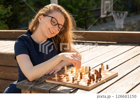Caucasian woman playing chess outdoors. 126681150