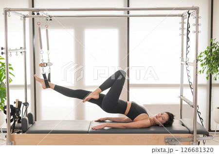 Asian woman doing pilates on reformer.  126681320