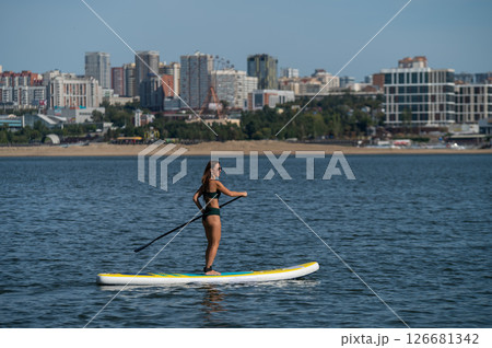 Caucasian woman posing on a SUP board. Summer sport. Caucasian woman posing on a SUP board. Summer sport. 126681342