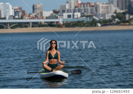 Caucasian woman doing yoga on a SUP board. Caucasian woman doing yoga on a SUP board. 126681493