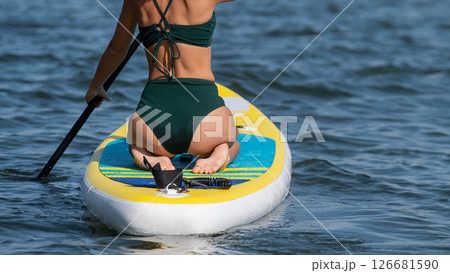 Caucasian woman riding a SUP board on the lake. Summer sport. Caucasian woman riding a SUP board on the lake. Summer sport. 126681590