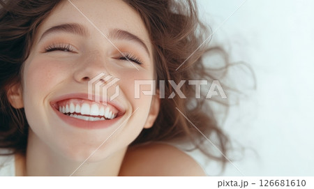 Young woman with closed eyes is lying on white background showing her beautiful smile and perfect white teeth after cosmetology or dentistry treatment 126681610