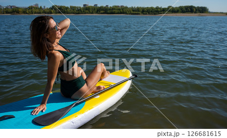 Beautiful caucasian woman is swimming on a SUP board. 126681615