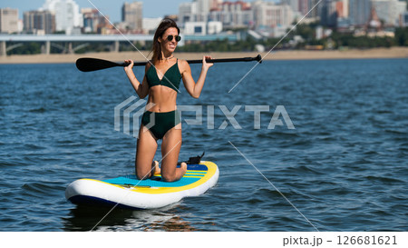 Caucasian woman riding a SUP board on the lake. Summer sport. 126681621