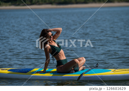 Caucasian woman doing yoga on a SUP board.  126681629