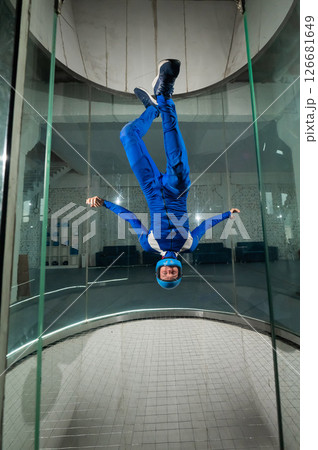 A man in overalls and a protective helmet enjoys flying in a wind tunnel. Free fall simulator A man in overalls and a protective helmet enjoys flying in a wind tunnel. Free fall simulator 126681649
