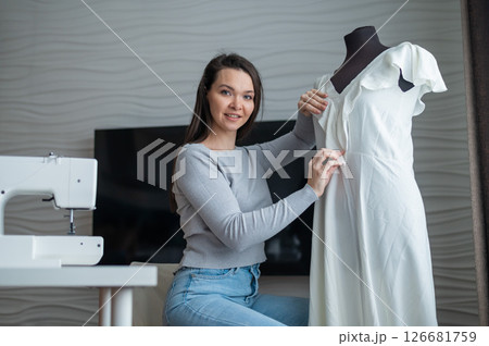 Caucasian woman sews a dress at home. Workspace of a seamstress 126681759