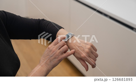 Elderly Caucasian woman looking at smart watch. Close-up of hands. Elderly Caucasian woman looking at smart watch. Close-up of hands. 126681893