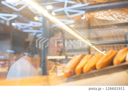 Caucasian woman looks greedily at baked goods in a bakery. Caucasian woman looks greedily at baked goods in a bakery. 126681911