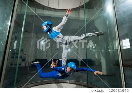 A male instructor teaches a woman how to fly in a wind tunnel. Free fall simulator. A male instructor teaches a woman how to fly in a wind tunnel. Free fall simulator. 126681946