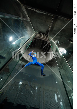 A man in overalls and a protective helmet enjoys flying in a wind tunnel. Free fall simulator 126681996