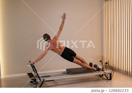 A man doing Pilates on a reformer. A man doing Pilates on a reformer. 126682233