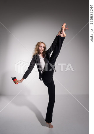 Barefoot ballerina in business suit dancing with a cup of coffee on a white background.  126682244