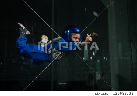 Caucasian boy flies in a wind tunnel.  126682332
