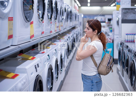 Caucasian woman chooses a washing machine in a home appliances store Caucasian woman chooses a washing machine in a home appliances store 126682363