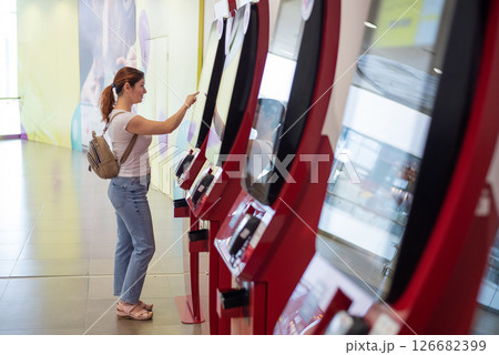 Caucasian woman buying cinema ticket at self-service box office. Caucasian woman buying cinema ticket at self-service box office. 126682399