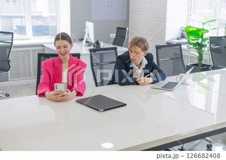 Caucasian Businesswoman Uses Smartphone While Colleague Has Problems At Work.  126682408