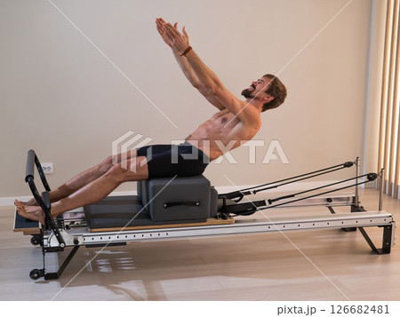 A man doing Pilates on a reformer.  126682481