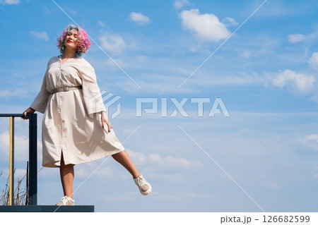 A woman with colored hair walks outdoors. Portrait of a girl against the blue sky.  126682599